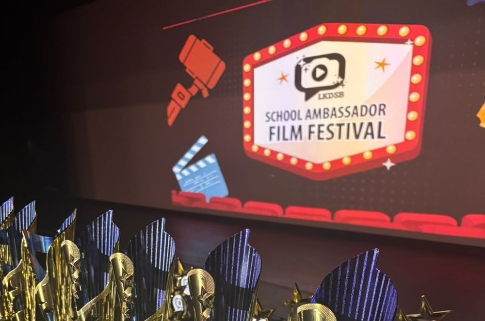 Trophies lined up in front of School Ambassador Film Festival screen