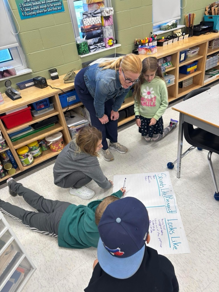 teacher bent over talking to 4 kids working on a respect assignment on ground