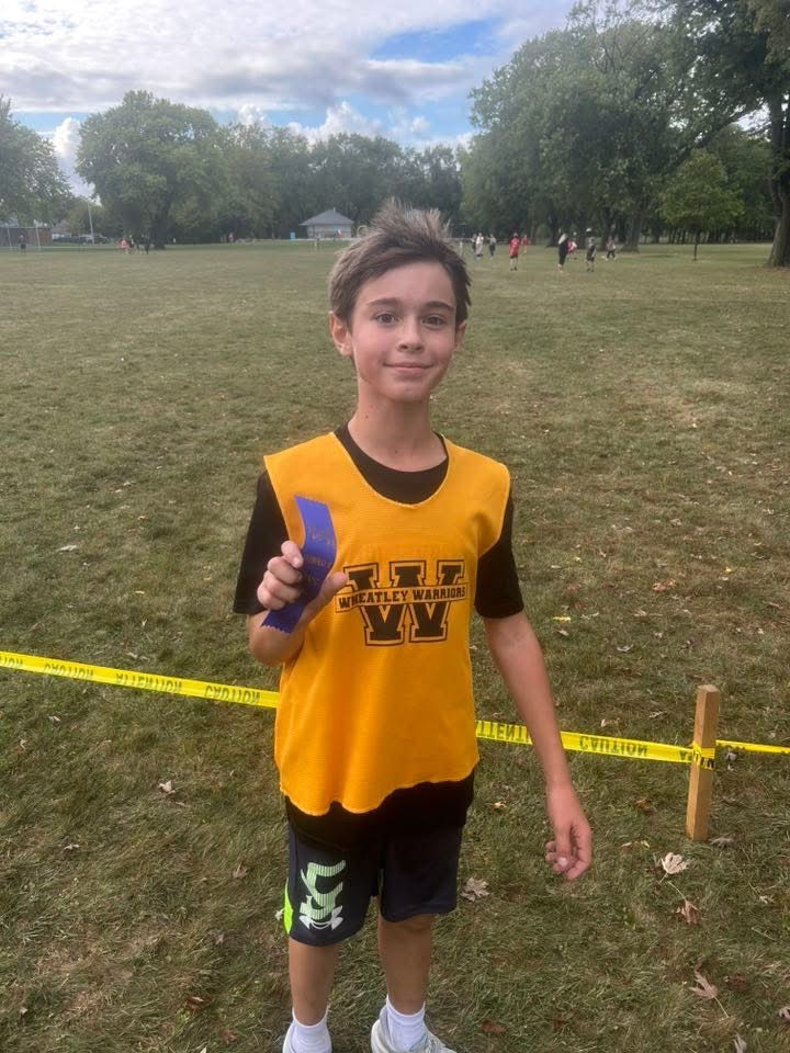 grade 6 boy standing with a ribbon after his running race