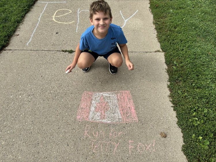 Child sitting beside sidewalk chalk drawing for