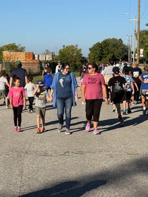 A teacher holding a student hand while walking for Terry Fox and a parent walking beside the teacher