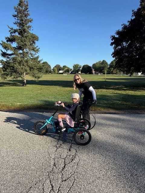 female student on her bike with a caring adult
