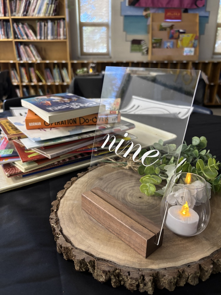 A table decorated with a centrepiece and a stack of books