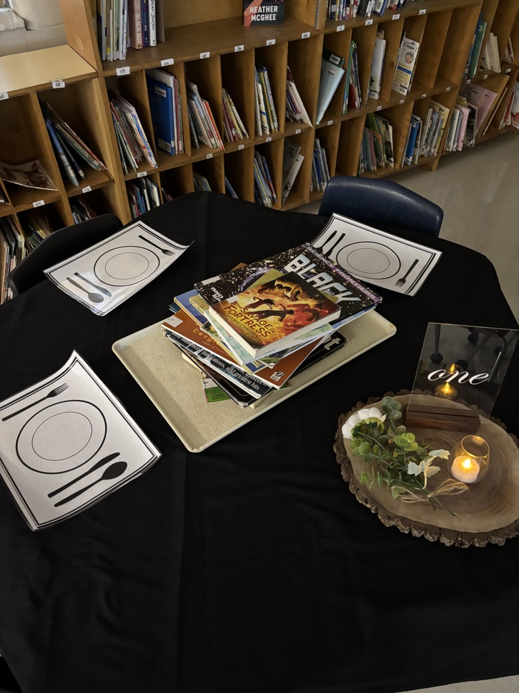 A table showing a stack of books surrounded by placemats