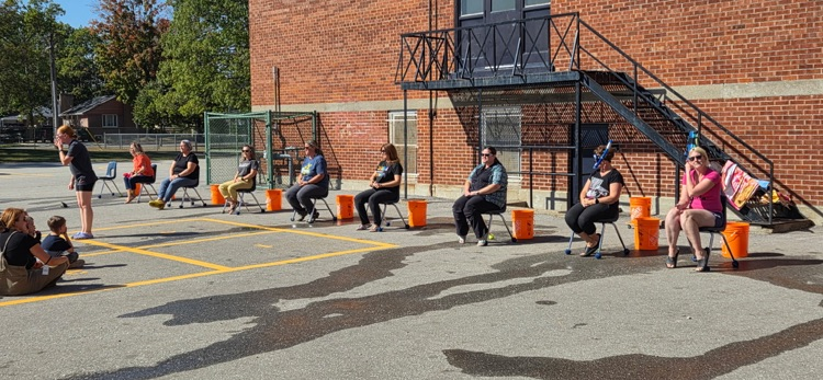 group of eight staff sitting on chairs outside for ice bucket challenge 