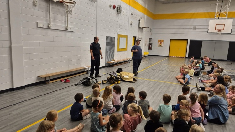 A large group of students in the Wheatley gym, listening to the firefighters
