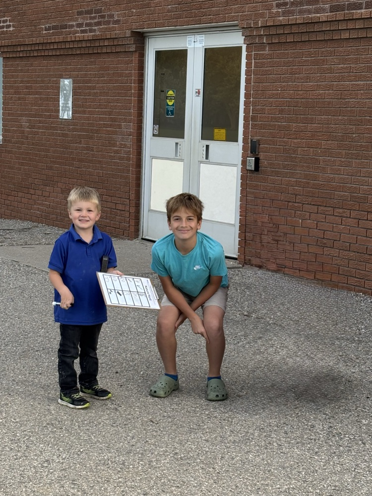 A kindergarten student and a grade 7 student smiling at the camera