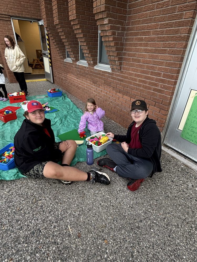 Two older students sitting with a younger student, smiling at the camera
