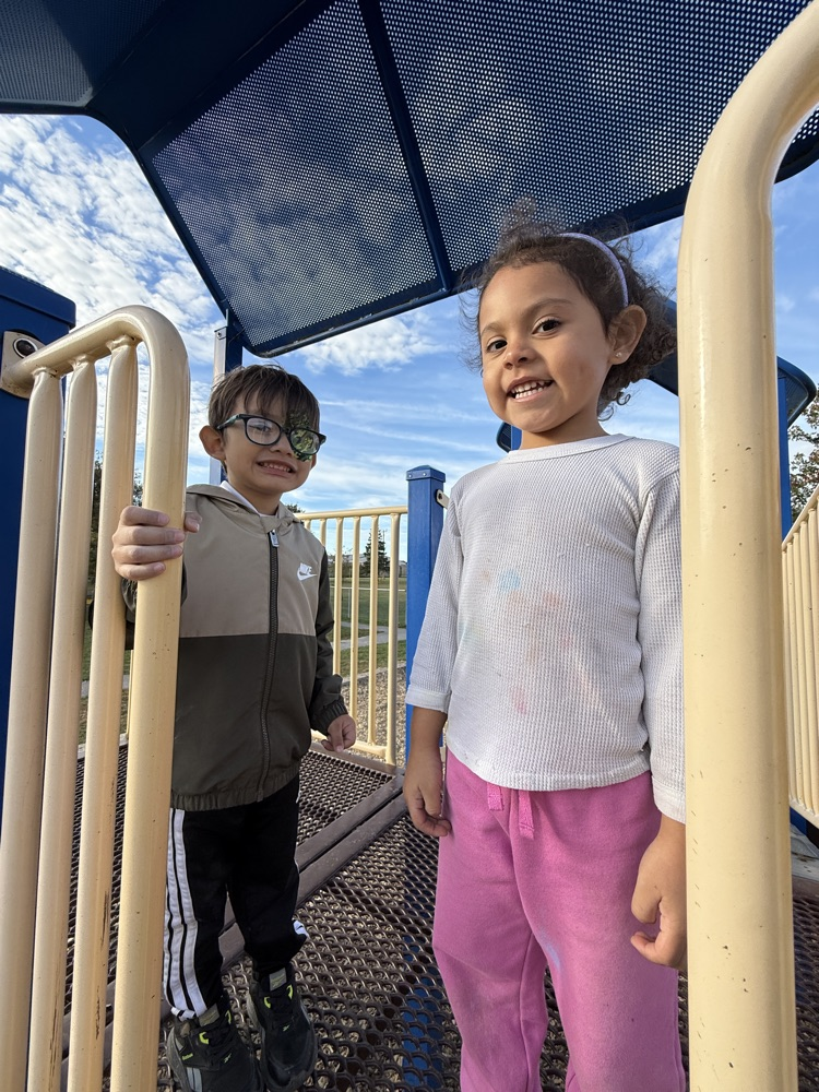 A boy and a girl in kindergarten standing on the playground, smiling