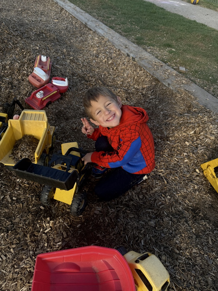 A boy in kindergarten playing with trucks in the mulch