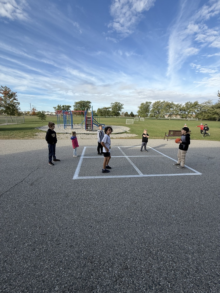 A group of students playing foursquare outside on the playground at school