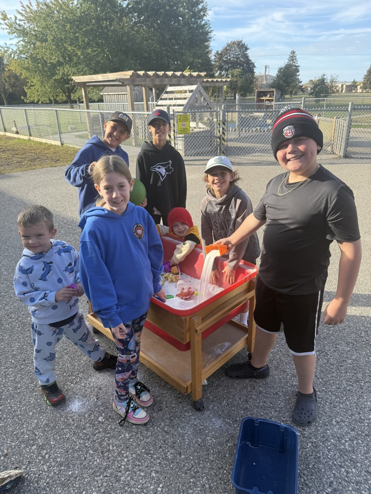 A group of students playing at the sandbox