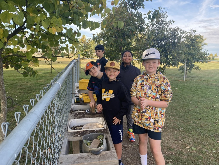 A group of older students playing in the mud kitchen in the kindergarten yard