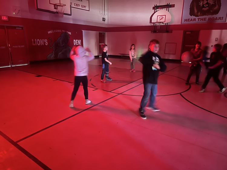 Students playing volleyball in a dark gym