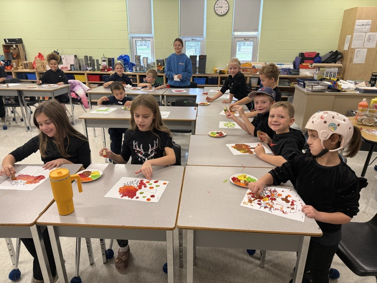 A group of students sitting at desks, painting, fall art