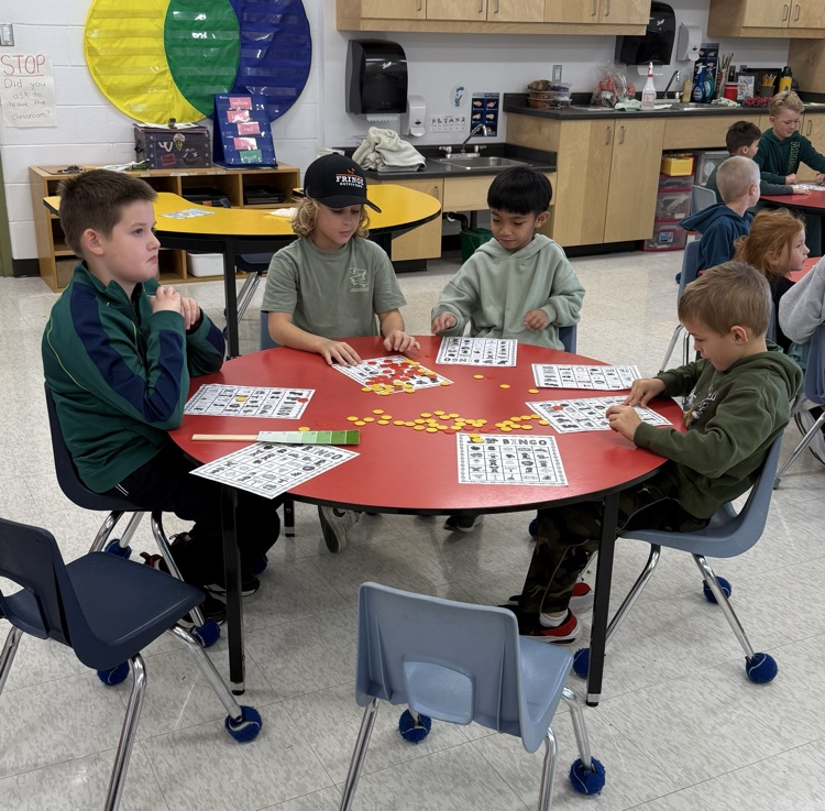 A group of student students sitting at a red table playing bingo