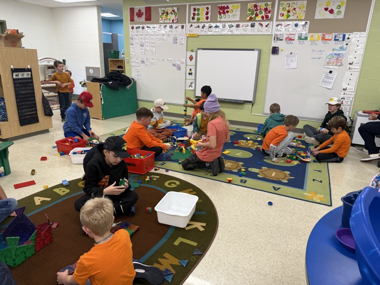 A classroom full of students sitting on the carpet playing with toys