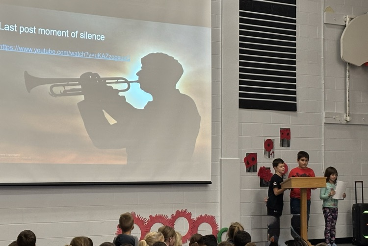 3 students taking the lead on the Remembrance Day ceremony in the gym