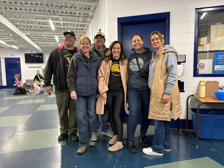 Group of parents and teachers smiling at the camera at the hockey game