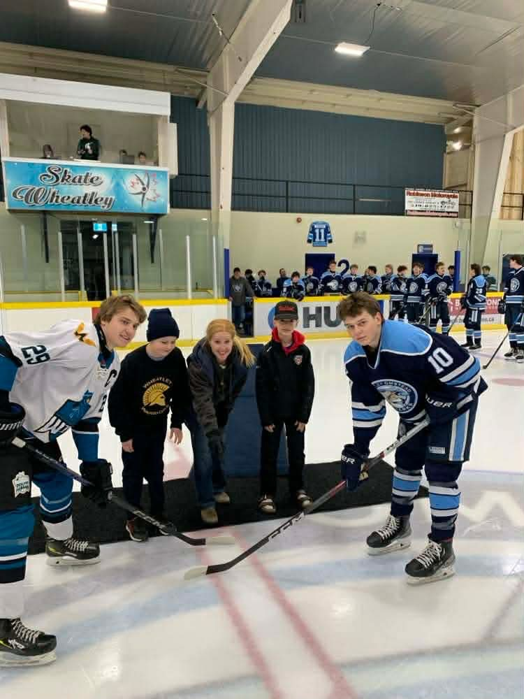 Commemorative puck drop with Mrs. Hopper and two students at the Wheatley sharks hockey game