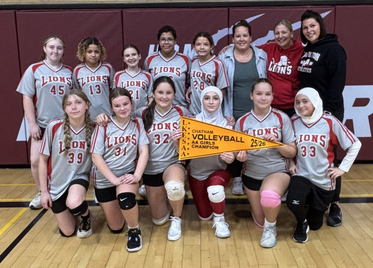 girls volleyball team posing with the championship pennant