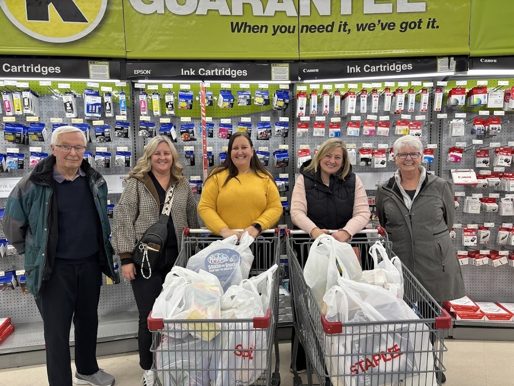 5 people at a store standing behind full shopping carts
