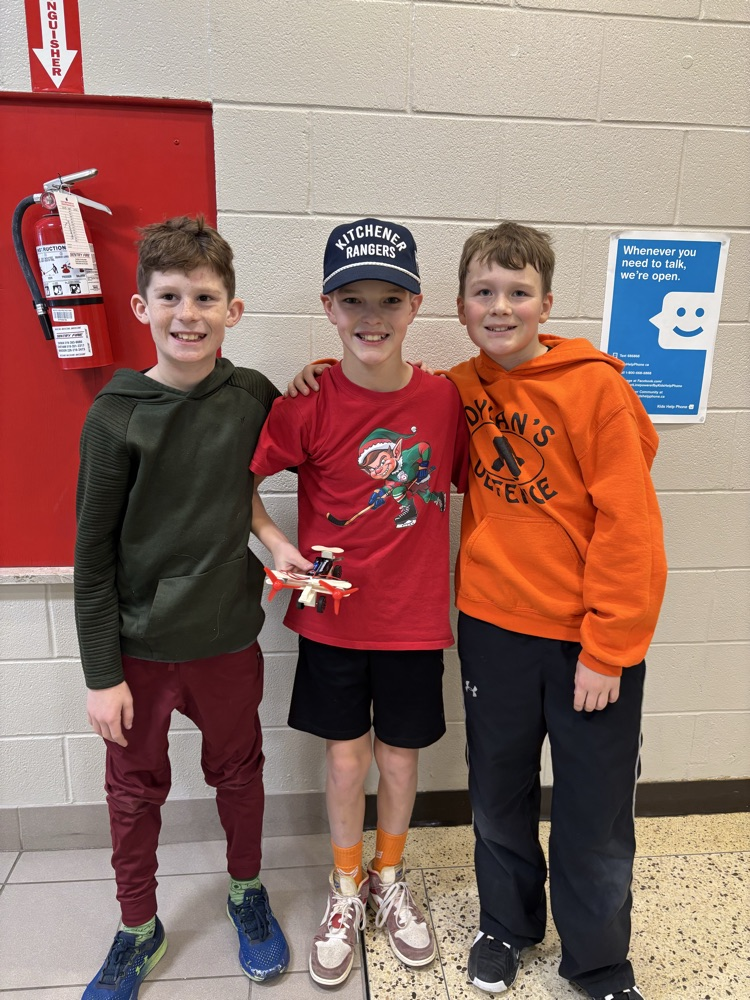 Three grade 6 boys with an airplane they created for science
