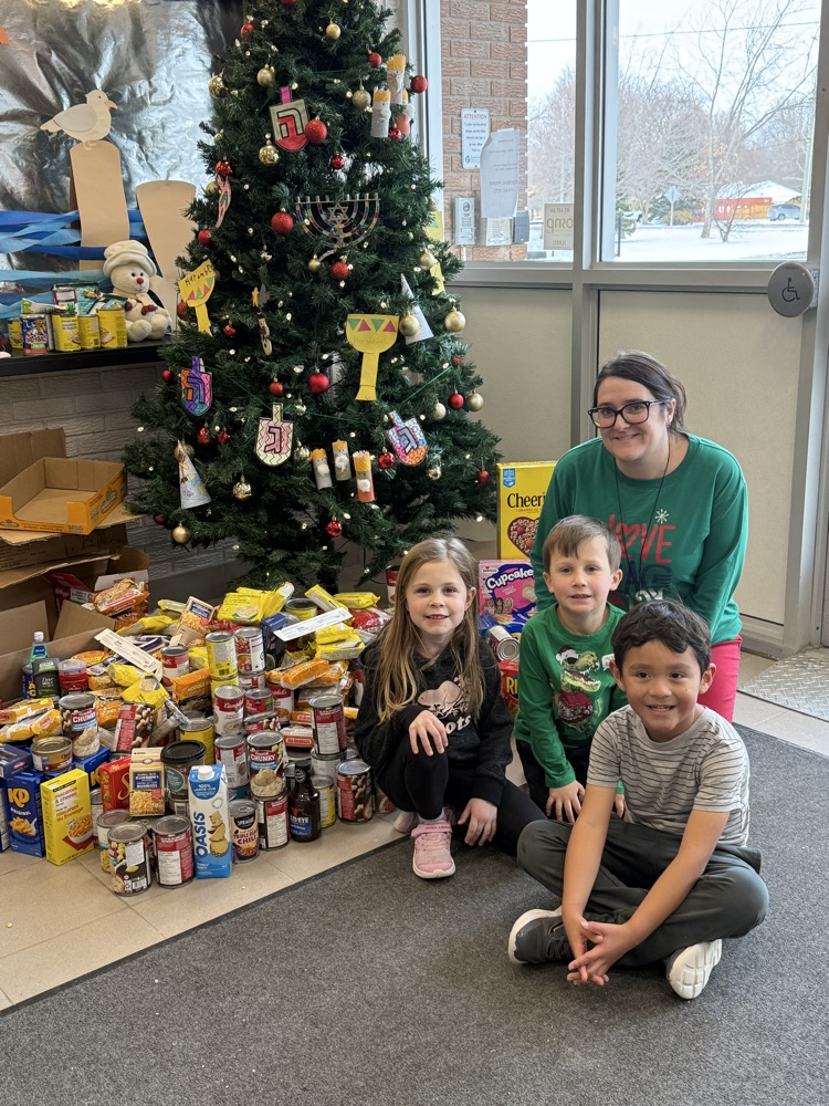 Wheatley Giving Tree with donation to the Village Resource Center with a teacher and 3 young students smiling in front of the tree