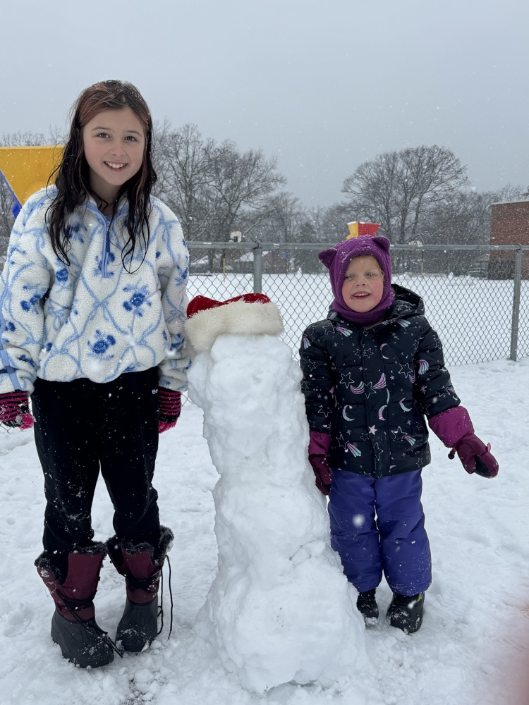 two people standing beside a snowman 