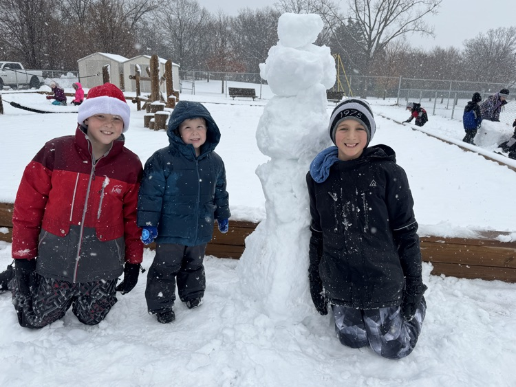 3 people standing with a snowman 