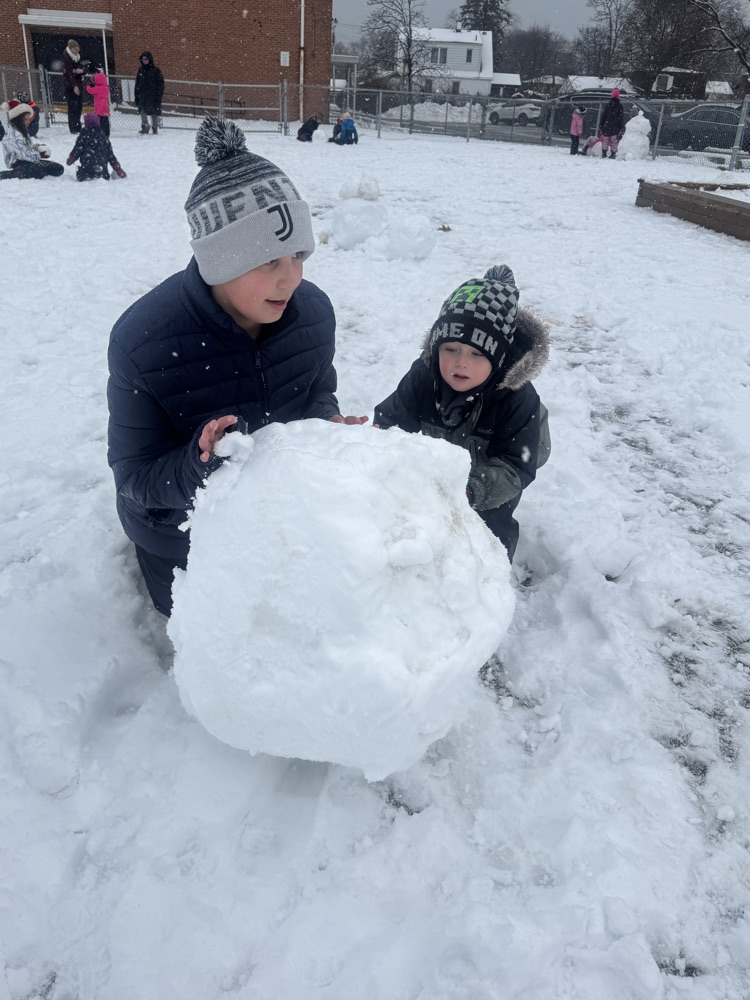 two people pushing a snow ball 