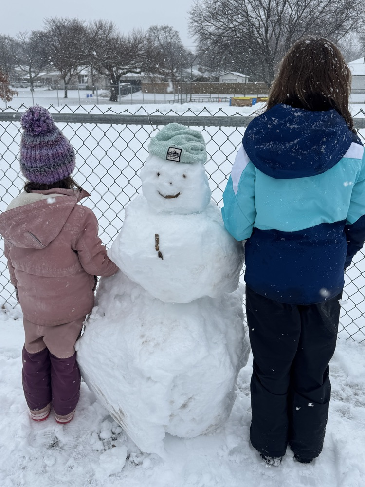two people beside a snowman with their backs to camera 