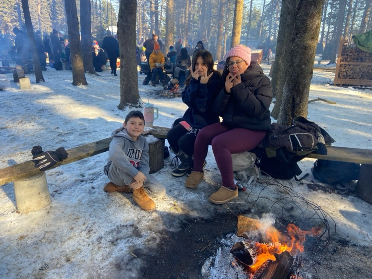 student sitting around a campfire in the winter