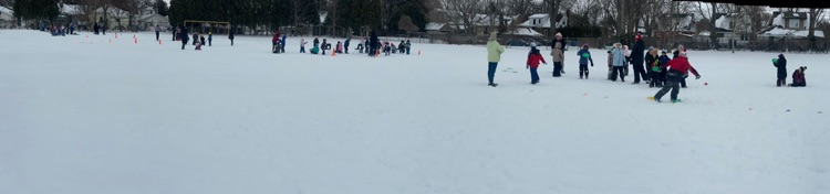 Panoramic shot of a schoolyard showing children playing in the snow