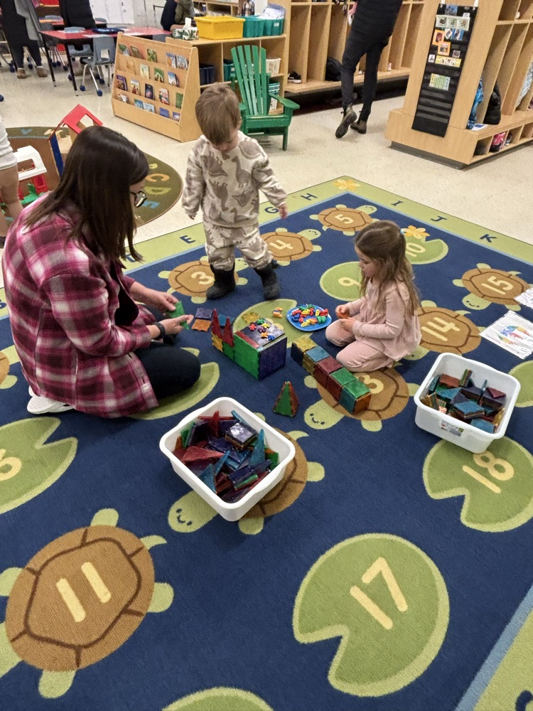 2 students playing on the carpet with their teacher