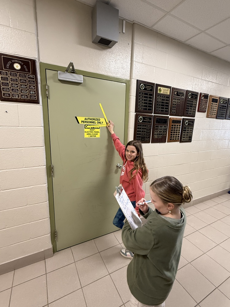 two females students investigating Angles on a sign on a door