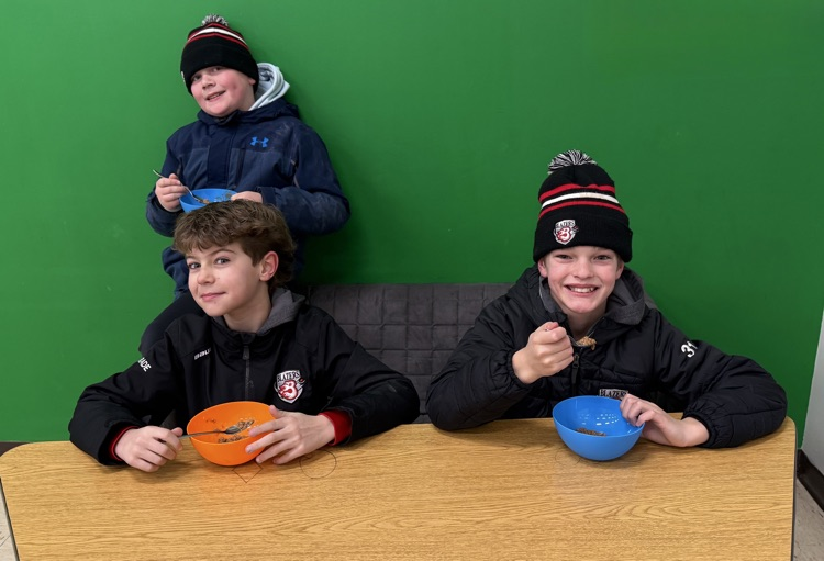 Three boys smiling at the camera with balls in their hands