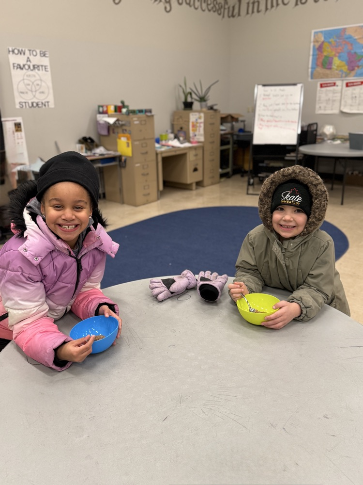 two young students eating their oatmeal, smiling at the camera