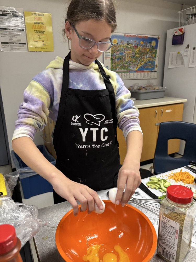 student cracking eggs into a bowl