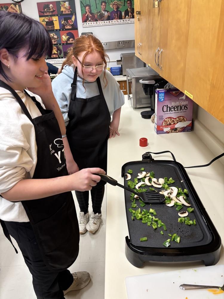 Students frying up vegetables on a grill
