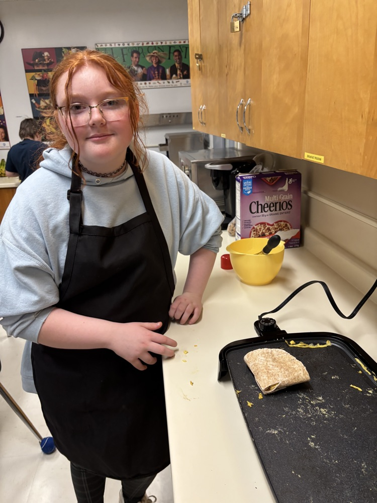 Student making quesadilla on a grill