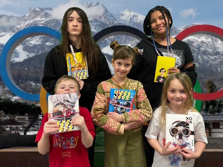 students standing in front of the Olympic rings, holding prizes they had won at school