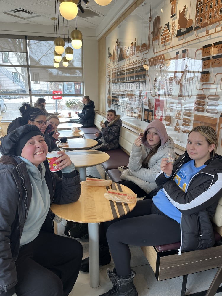 Students sitting having hot chocolate and donuts at a local coffee shop