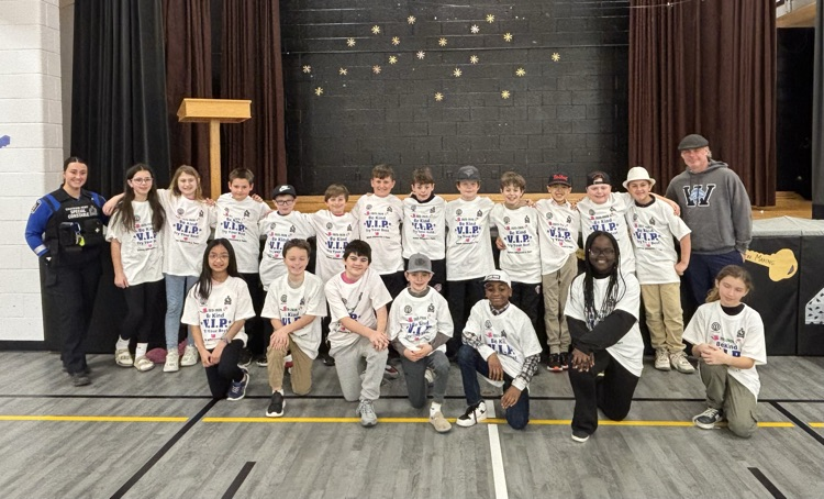 grade 5 students smiling for the camera with Constable Oswald, and Thomas Grubb wearing their new VIP T-shirts