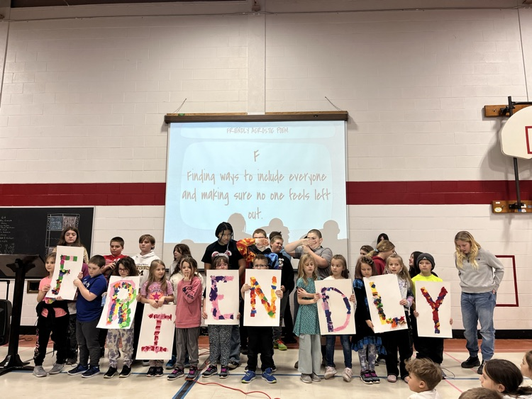 students in a line holding up posters that spell friendly