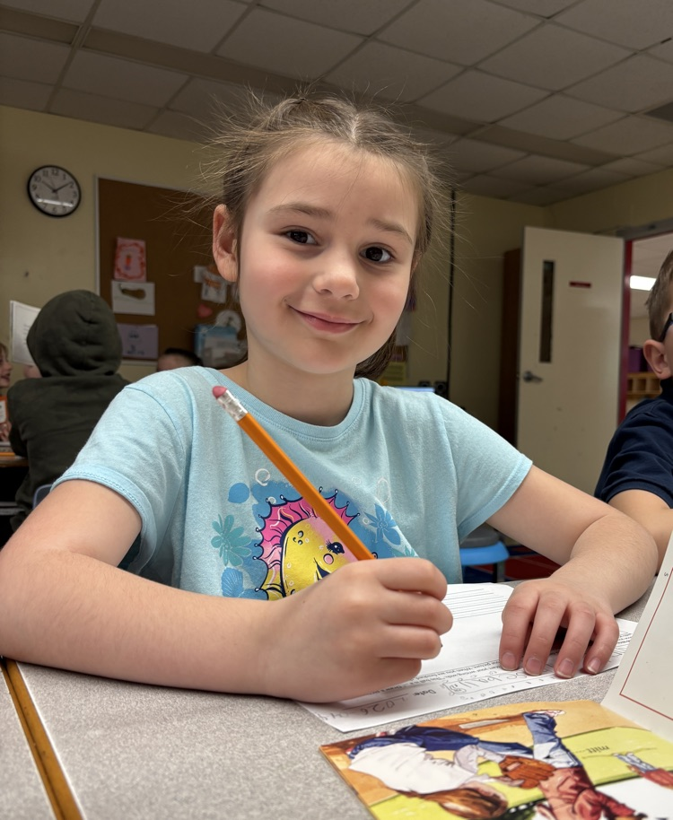 Student reading a book and writing on a worksheet
