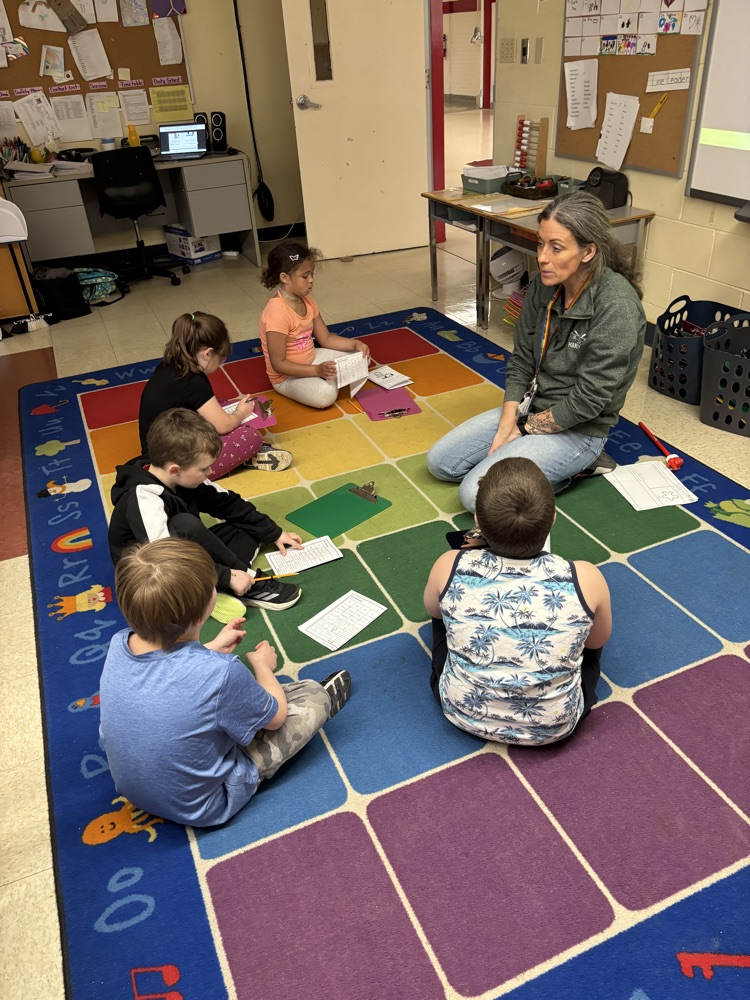 Teacher working with a small group of student students reading on the carpet