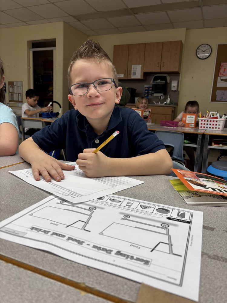 Student reading a book while writing on a worksheet