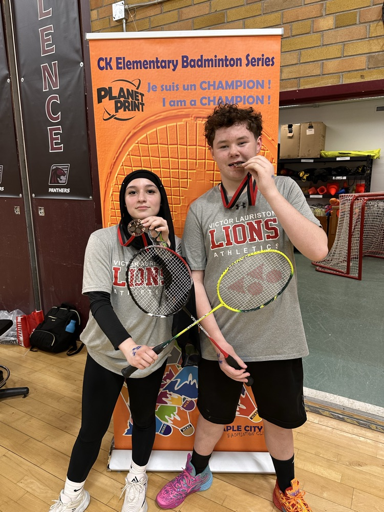 students holding badminton rackets and medals they won in a tournament