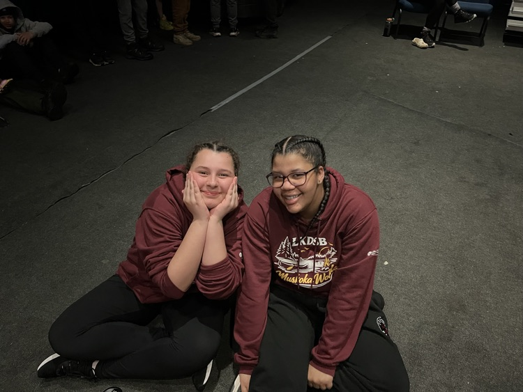 two students sitting on the floor posing for the